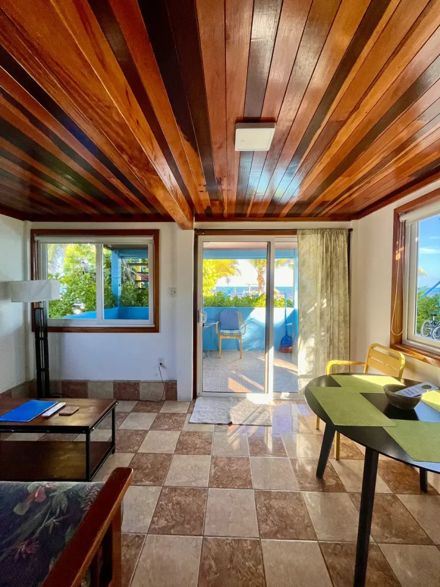 Bright living and dining area with ocean view through the balcony doors at Colinda Cabanas in Caye Caulker, Belize