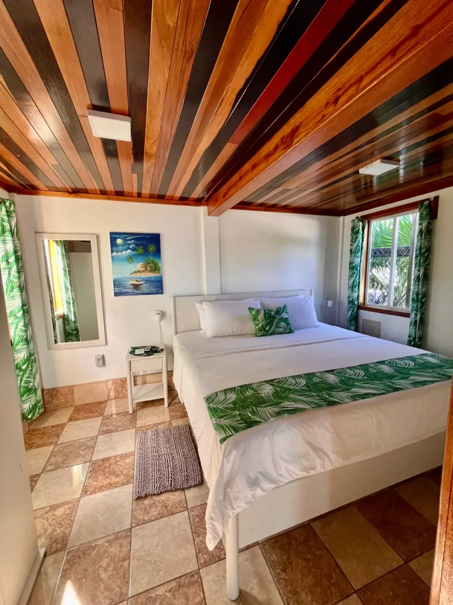 Bright, comfortable bedroom with a king bed and tropical decor at Colinda Cabanas in Caye Caulker, Belize