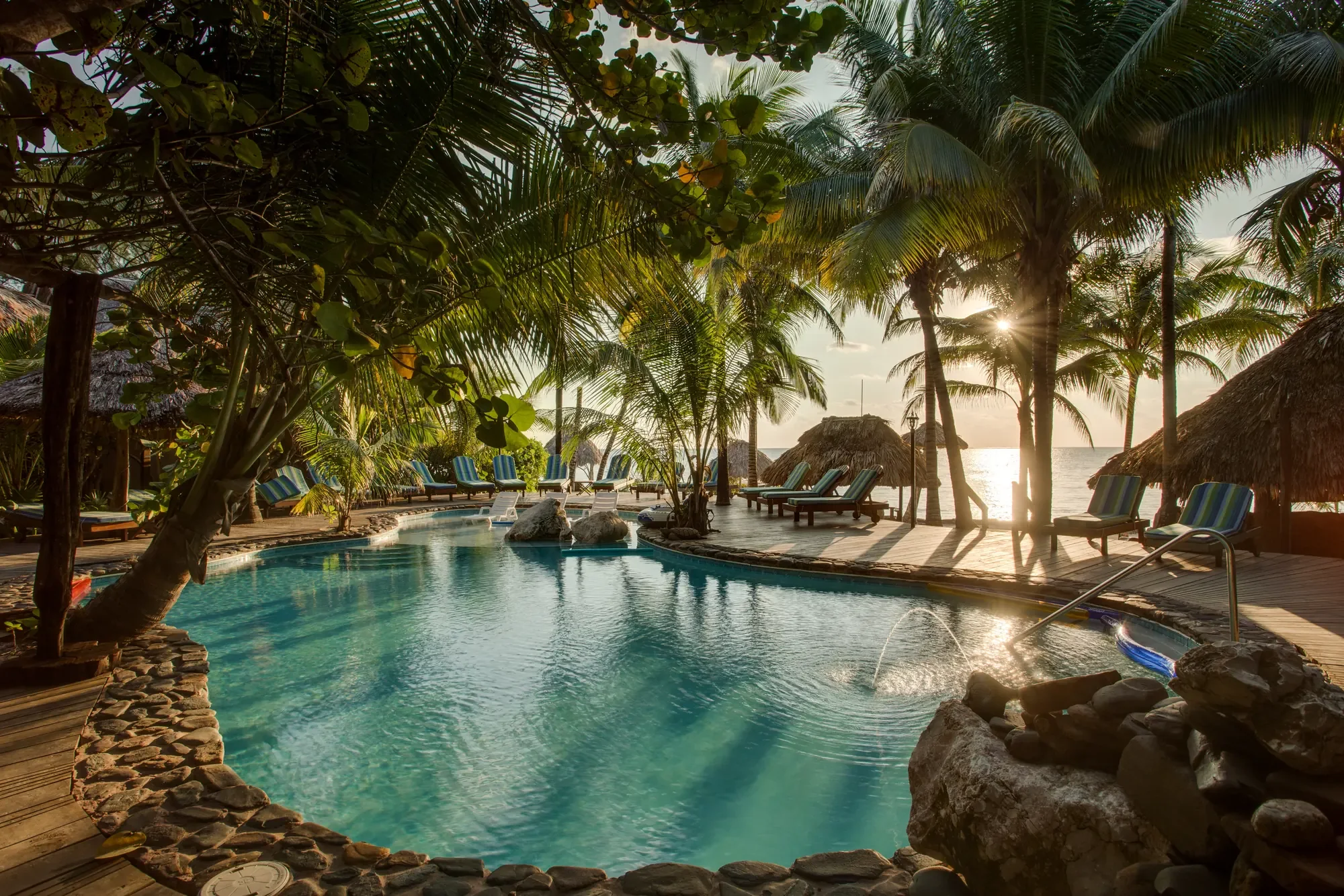 Xanadu Island Resort's palm-fringed pool overlooking the Caribbean Sea at sunrise in San Pedro, Belize.